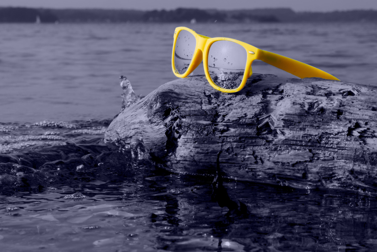Eine gelbe Sonnenbrille liegt auf einem Felsen im Wasser