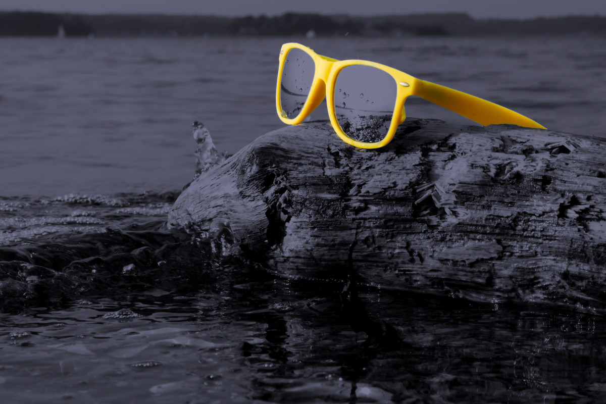 Eine gelbe Sonnenbrille liegt auf einem Felsen im Wasser