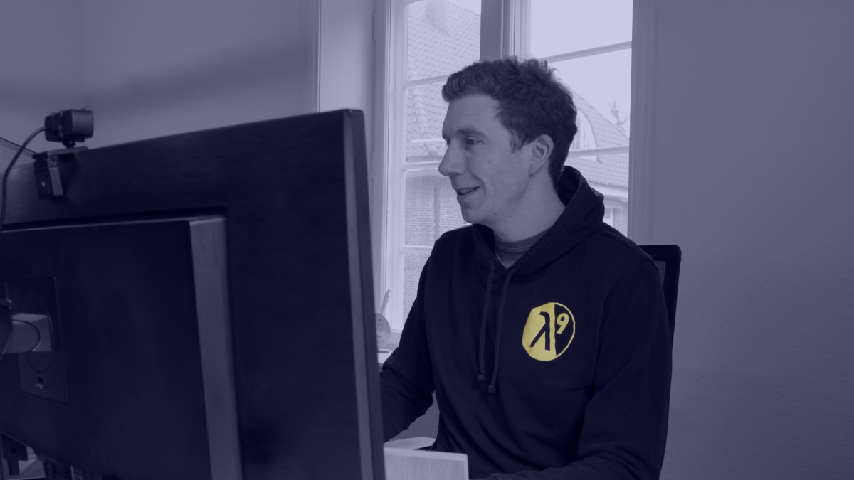 Mitarbeiter in einem Hoodie mit lambda9-Logo arbeitet an einem Computer im Büro.