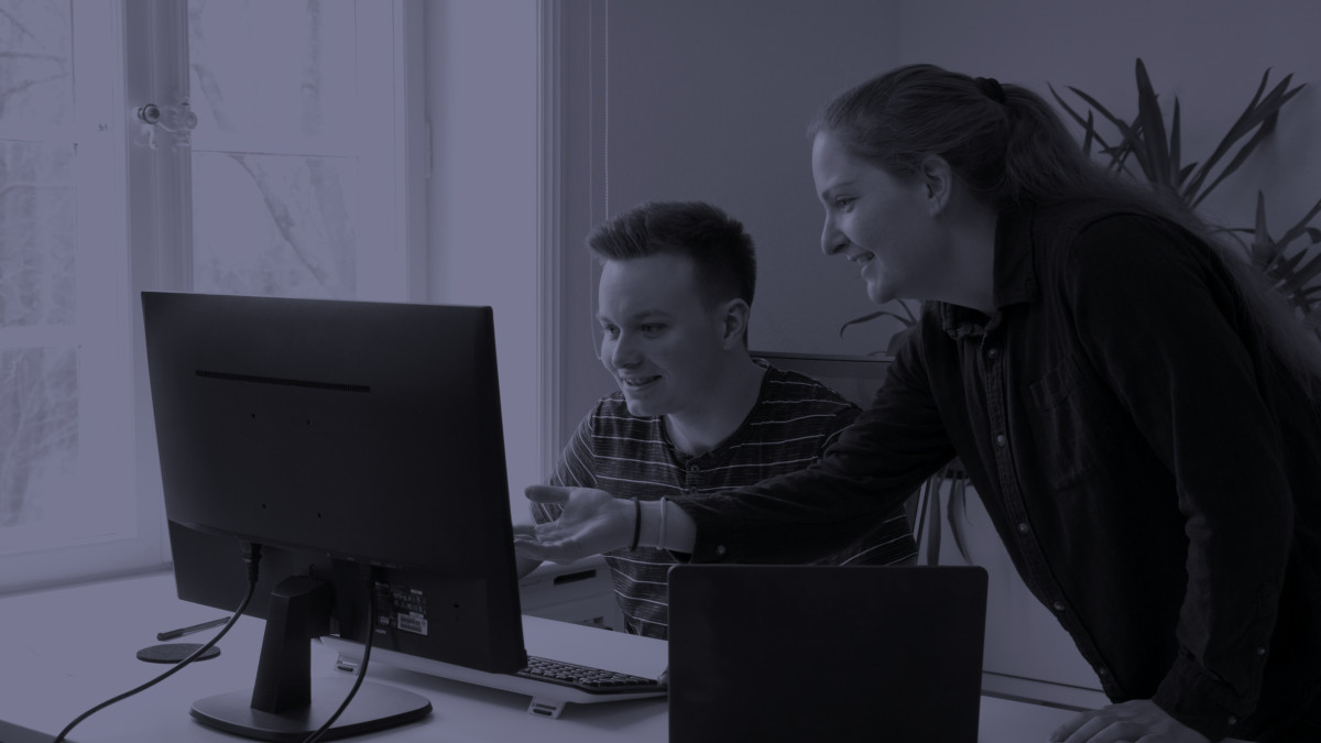 Two people in front of a monitor talking
